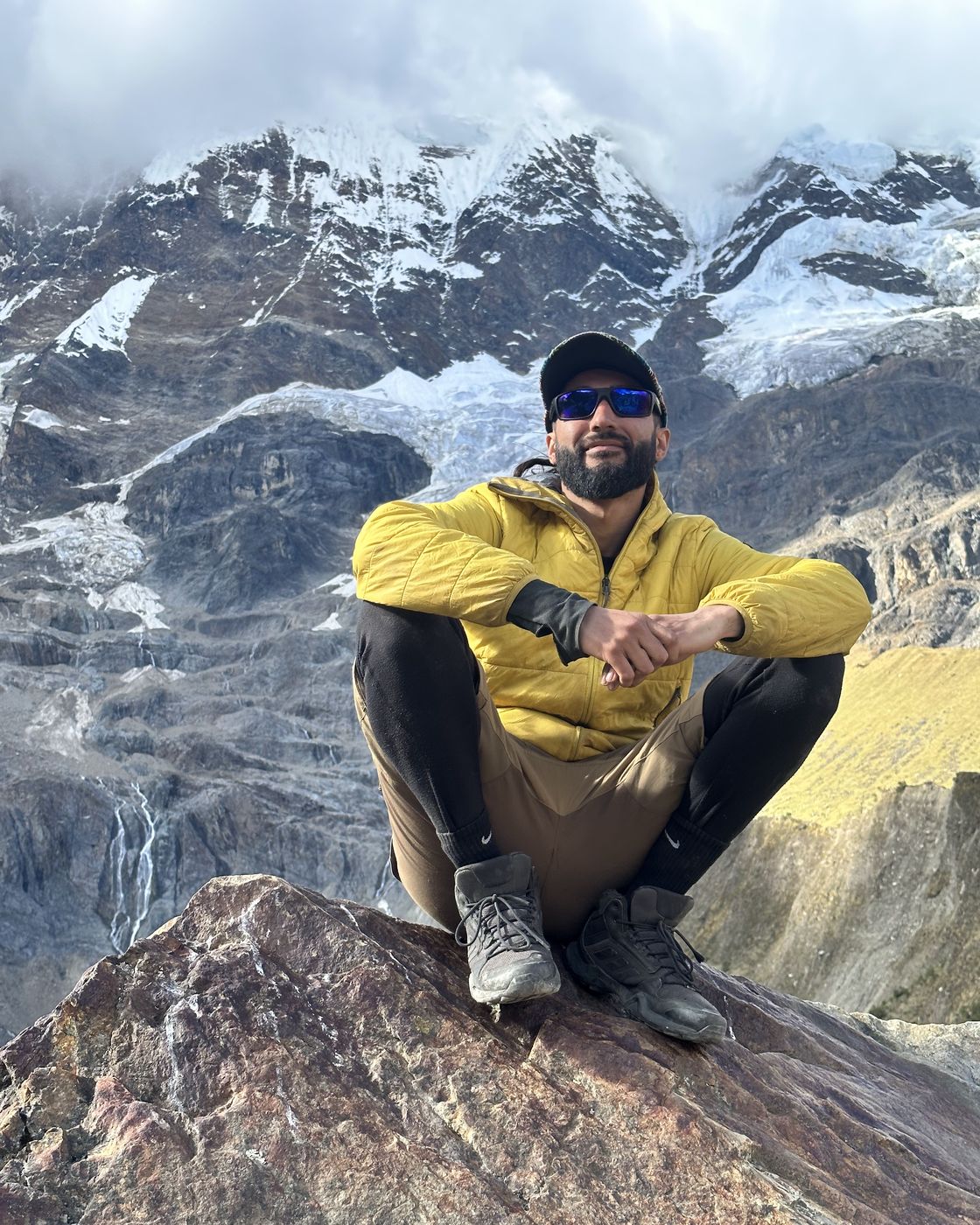 Diego Peñailillo sentado sobre una roca frente a montañas nevadas